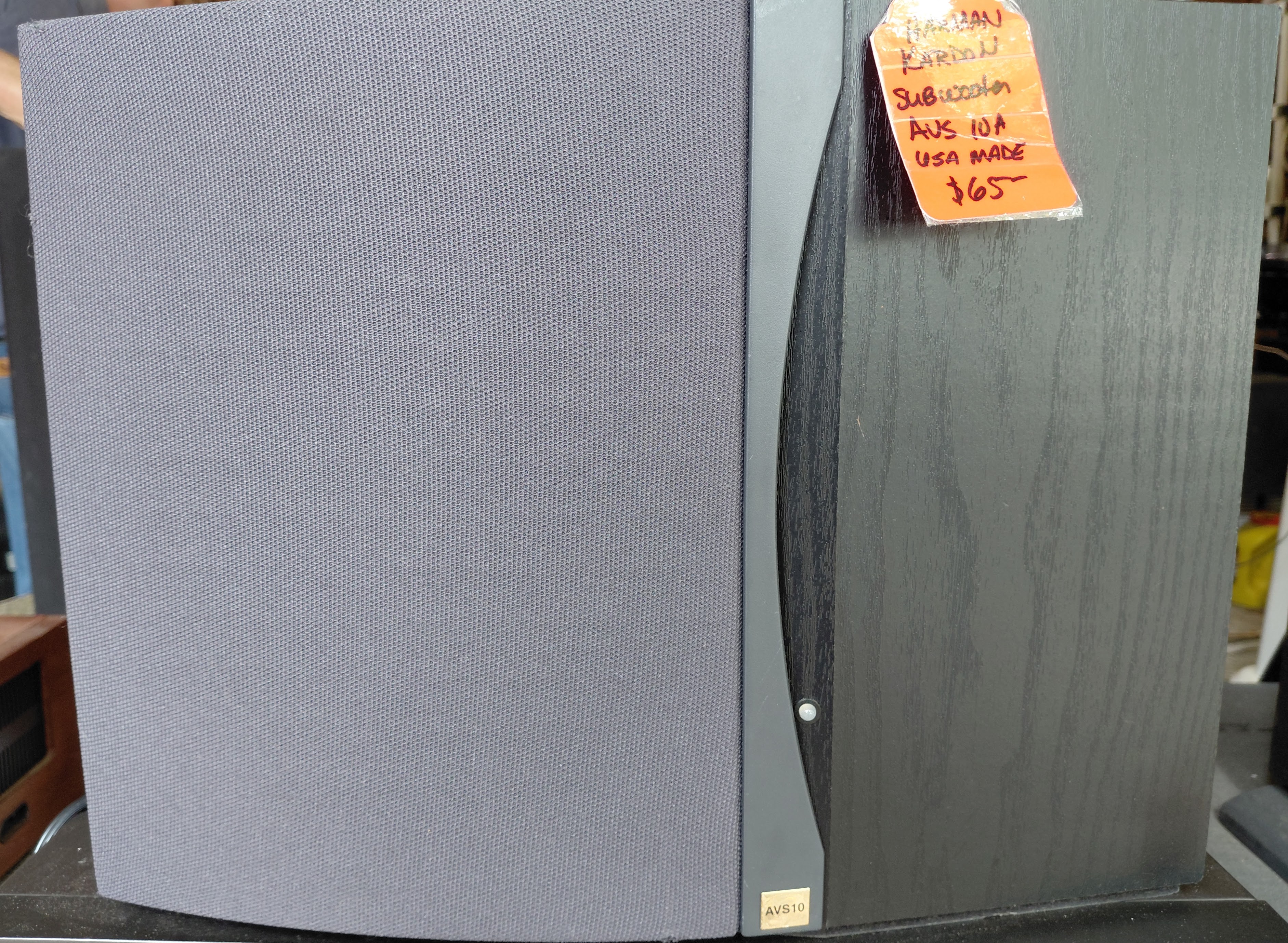 Harman/Kardon AVS10 powered subwoofer in black finish, shown in a workshop.